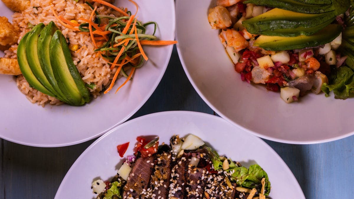 Three flavorful dishes featuring seafood and avocado, plated creatively for a delightful meal.